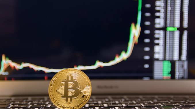 Bitcoin mit Kursentwicklung im Hintergrund