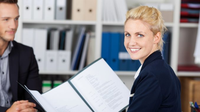 Junge Frau im Vorstellungsgespräch mit Bewerbungsmappe