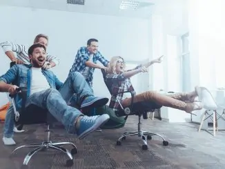 Angestellte sitzen fröhlich auf Bürostühlen im Büro