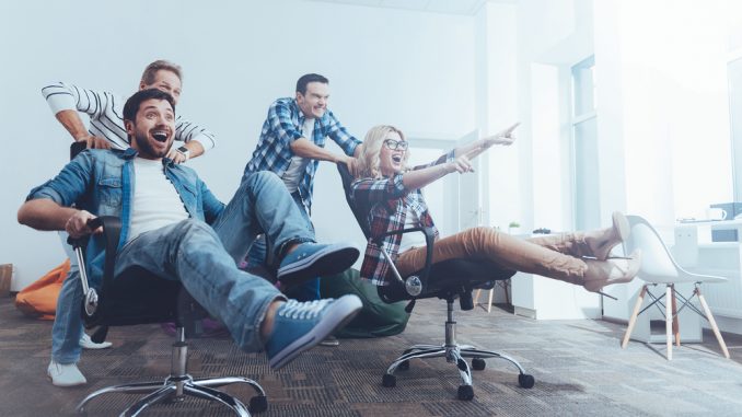 Angestellte sitzen fröhlich auf Bürostühlen im Büro