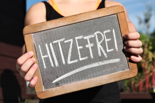 Ein Kind hält ein Schild hoch auf dem Hitzefrei steht