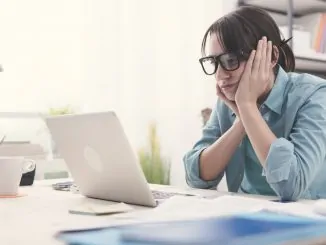 Eine Frau sitzt enttäuscht vor dem Notebook