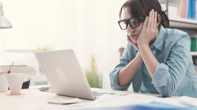 Eine Frau sitzt enttäuscht vor dem Notebook