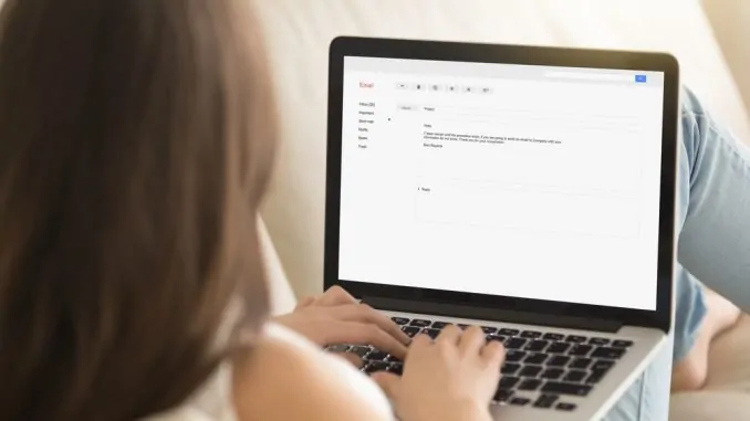 Eine junge Dame schreibt eine E-Mail am Notebook