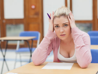 Ein junges Mädchen sitzt verzweifelt in der Schule an einem Tisch