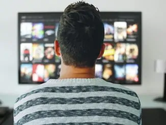 Ein junger Mann mit schwarzen Haaren sitzt vor dem TV