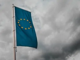 Eine blaue gelbe Fahne der europäischen Union weht im Wind vor dunklen Wolken