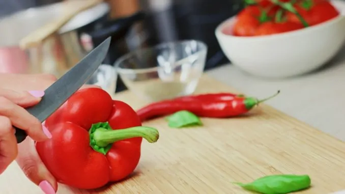 Frau schneidet rote Paprika mit einem Messer