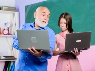 Zurück zur Schule. Kind unterrichten. Internet-Kurse. Moderne Schule. Moderner Pädagoge. Lehrer helfen Schulmädchen. Kleines Mädchen mit Manntutor-Studiengrifflaptop. Online-Unterricht. Lehrer für digitale Wissenschaft