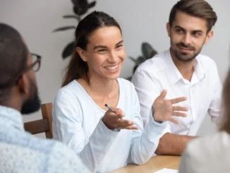 Glücklicher Frauenführertrainermentor, der mit Angestellten bei der Sitzung spricht