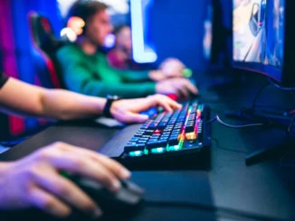 Professioneller Cybervideospieler-Studioraum mit PC-Lehnsessel, Tastatur für Strom im Neonfarbunschärfehintergrund. Weicher Fokus