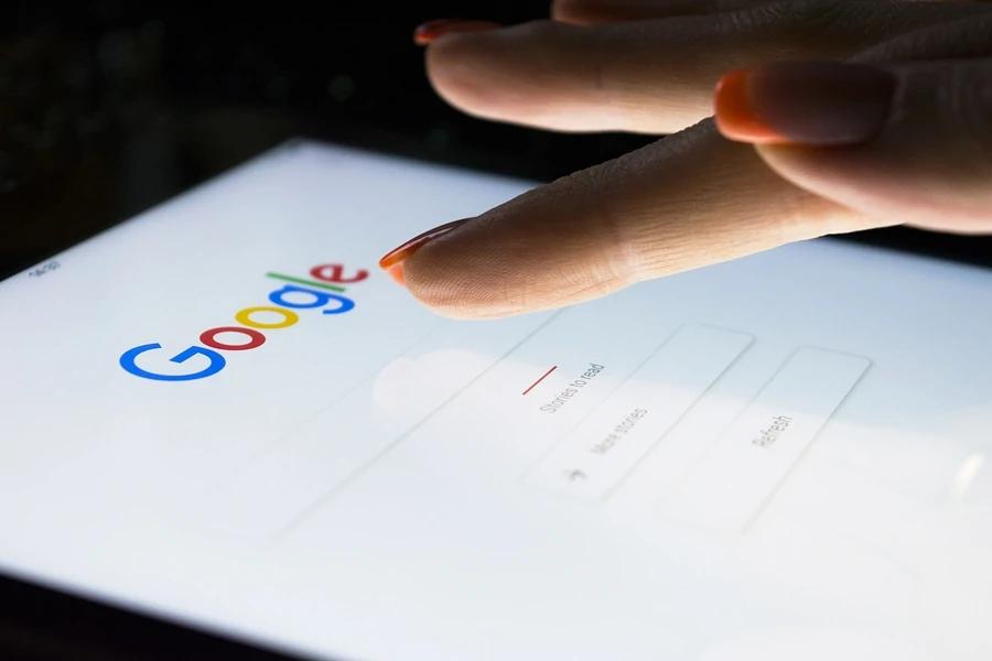Die Hand einer Frau berührt Bildschirm auf Tablet-Computer iPad Pro nachts für das Suchen auf Google-Suchmaschine. Google ist die beliebteste Internet-Suchmaschine der Welt.