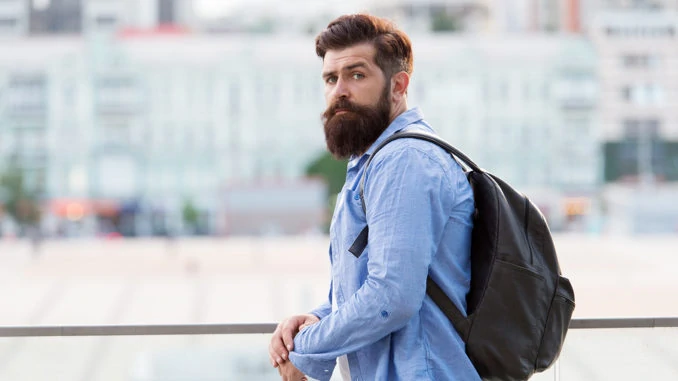 Rucksack für Reisen und Stadtleben. Hipster trägt Rucksack im lässigen Stil auf urbanem Outdoor. Bärtiger Mann, der mit Rucksack in den Sommerferien reist. Rucksack auf Rucksackreise mitnehmen.