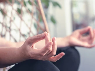 Ältere Frau, die Yoga zu Hause macht. Ältere Frau Hände in Yoga-Position. Älterer Rentner, der zu Hause Yoga macht. Frau Senior in der Yoga-Position im Schaukelstuhl. Yoga. Meditation. Ältere Frau.