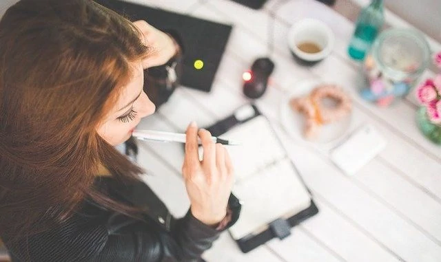 Eine junge Dame sitzt am Tisch und lernt für das Studium.