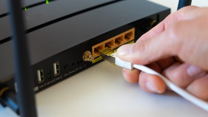 Hand steckt LAN-Label in den Router