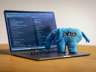 Blauer Stoffelefant mit PHP Logo steht auf Notebooktastatur