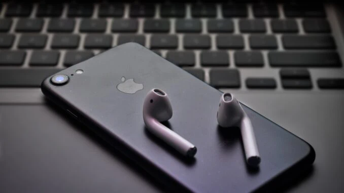 Iphone liegt umgedreht auf Tisch mit Airpods darauf