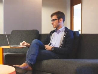 Mann sitzt auf Sofa am Laptop