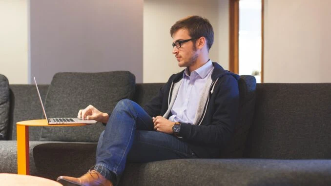 Mann sitzt auf Sofa am Laptop